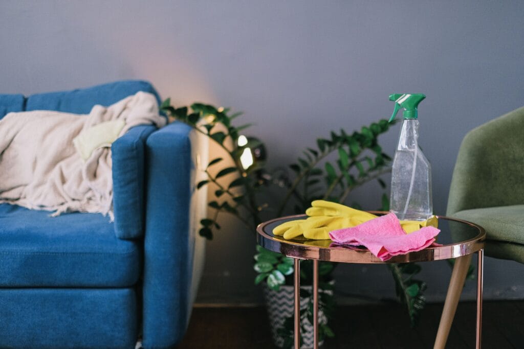 Cleaning supplies in a basket in a tidy living room, ready to clean the home room by room